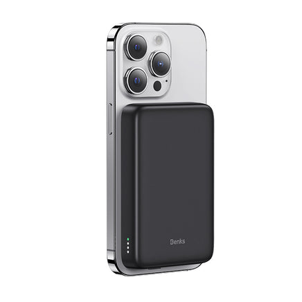 A black power bank magnetically attached to the back of a silver iPhone, showcasing its sleek and compact design.