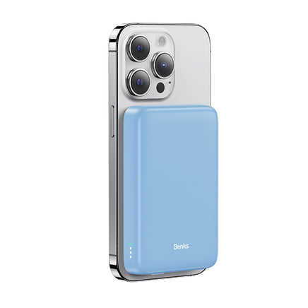 A blue power bank magnetically attached to the back of a silver iPhone, showcasing its sleek and compact design.