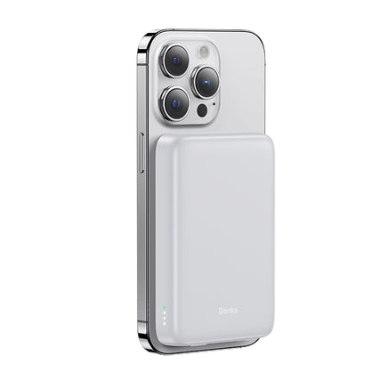 A white power bank magnetically attached to the back of a silver iPhone, showcasing its sleek and compact design.